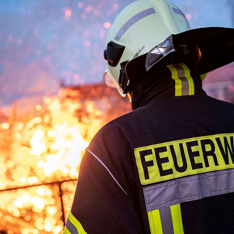 Ein Feuerwehrmann mit Brandschutzkleidung löscht ein Feuer - Brandschutz im Hotel