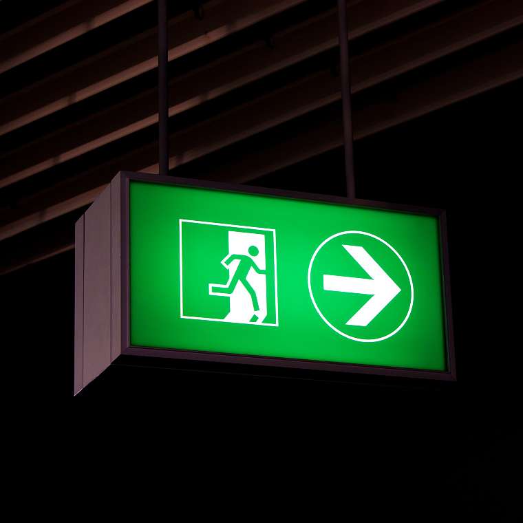 Ein grünes Leuchtschild zeigt des Fluchtweg im Falle eines Feuers