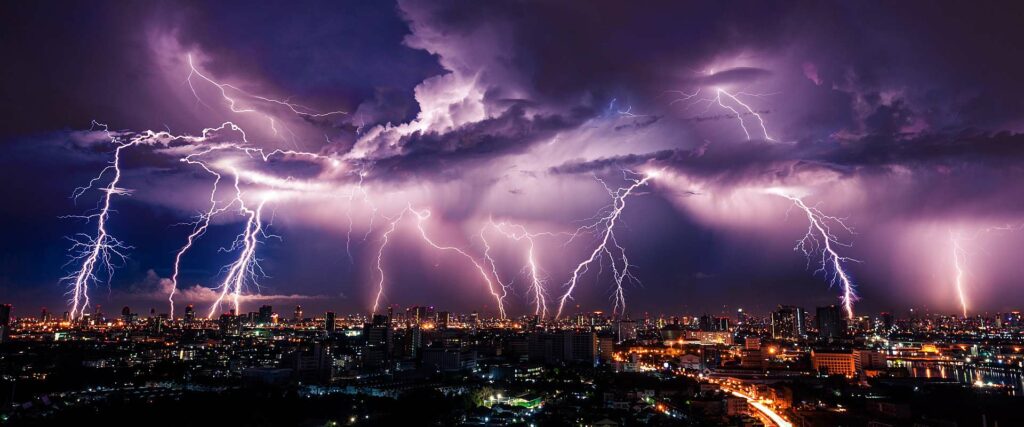 ein heftiges Gewitter mit vielen Blitzen zieht über eine Stadt. Zeit über Blitzschutz nachzudenken.